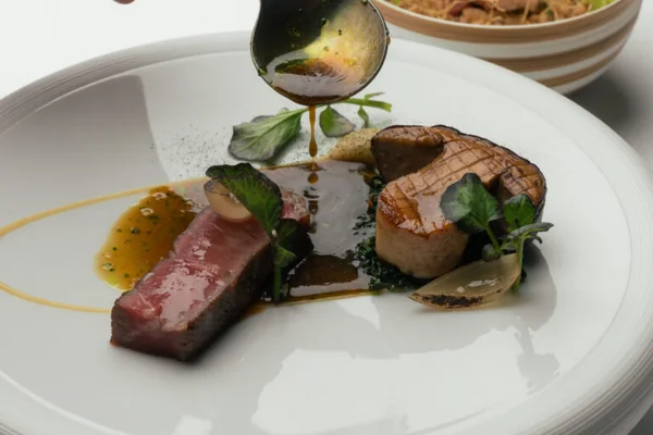 A plated dish being finished with sauce at Da Terra