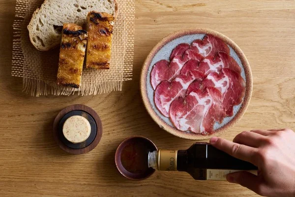 Grilled bread, butter and charcuterie, with olive oil being poured, at Maré in Hove