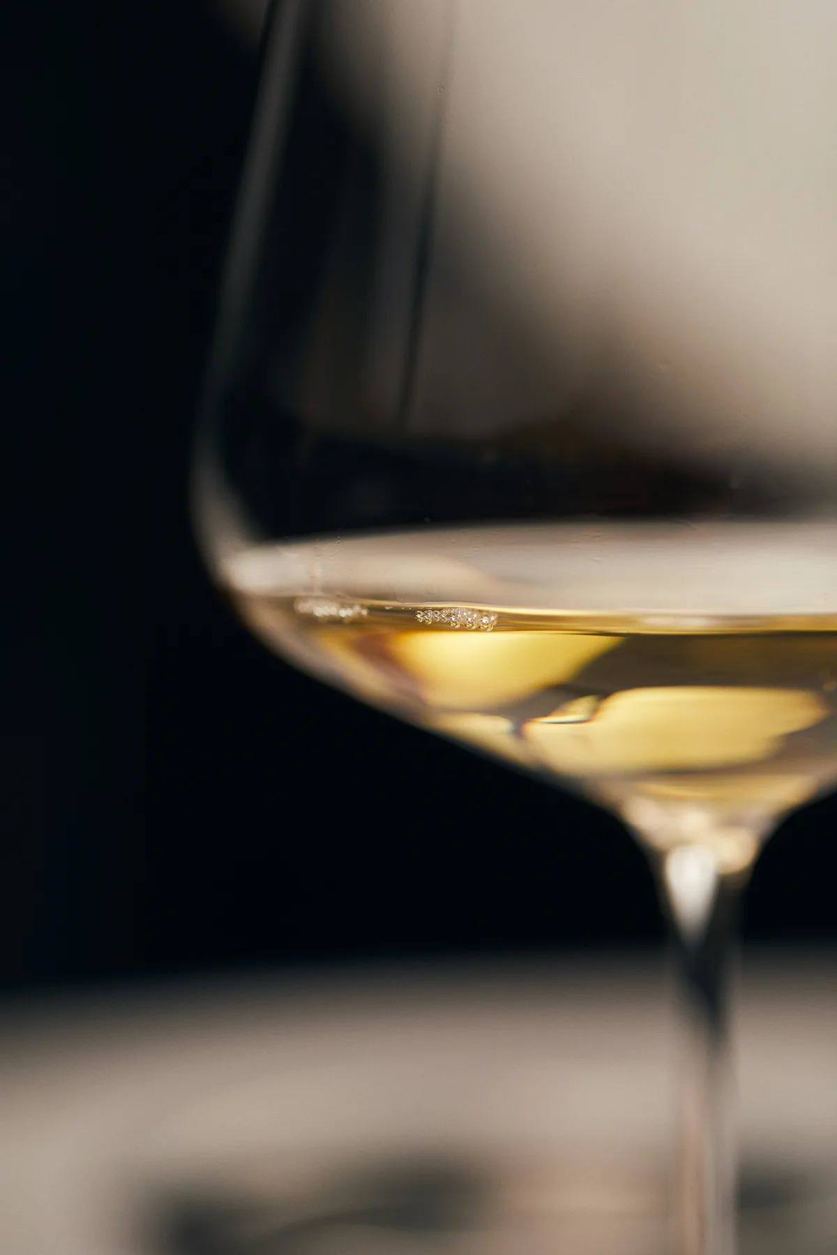 A glass of white wine, close up, against a dark background.