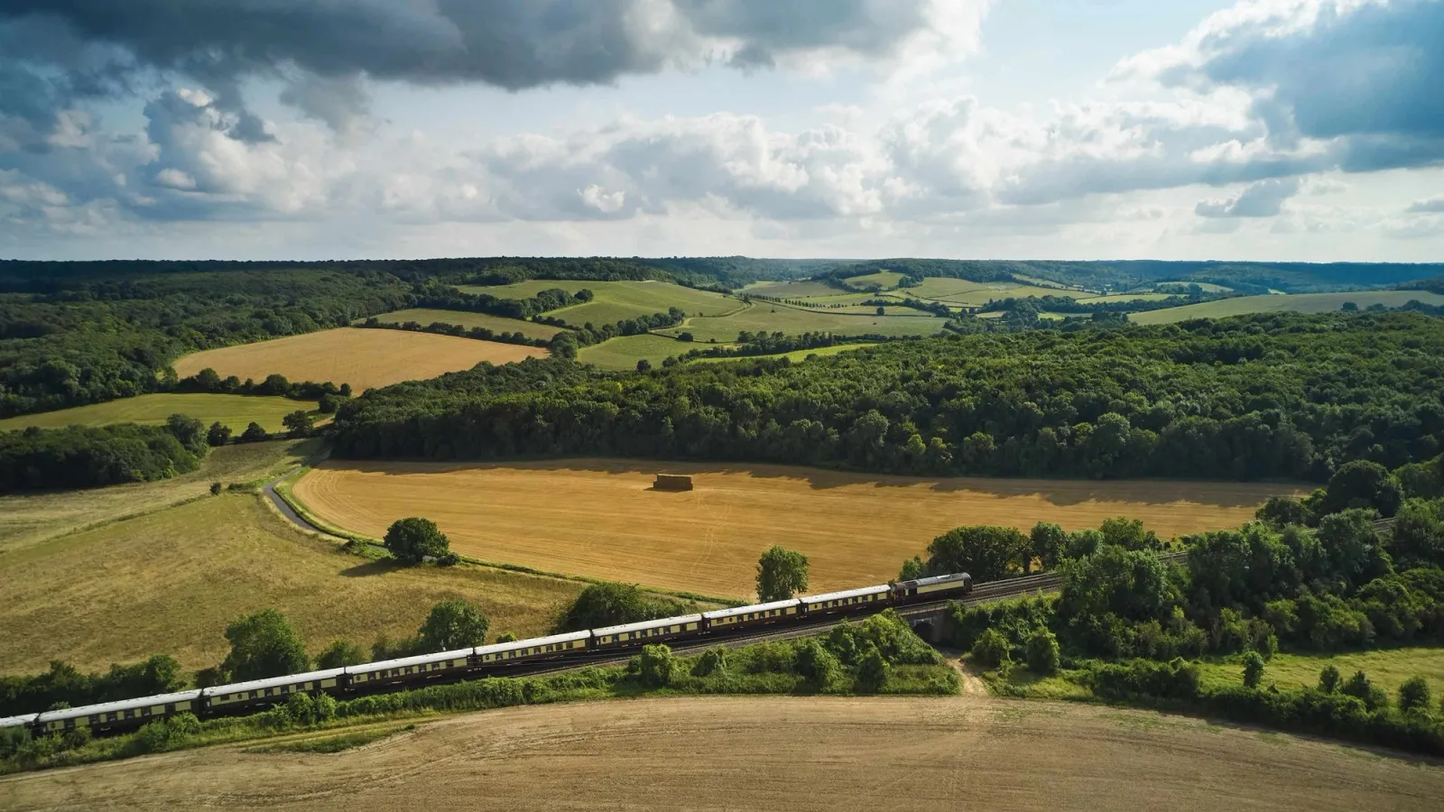 The British Pullman’s carriages crossing open farmland.