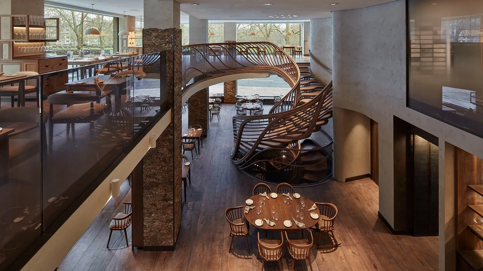 HIDE’s dining room seen from the floor above, with the oak staircase curving down to a laid table.