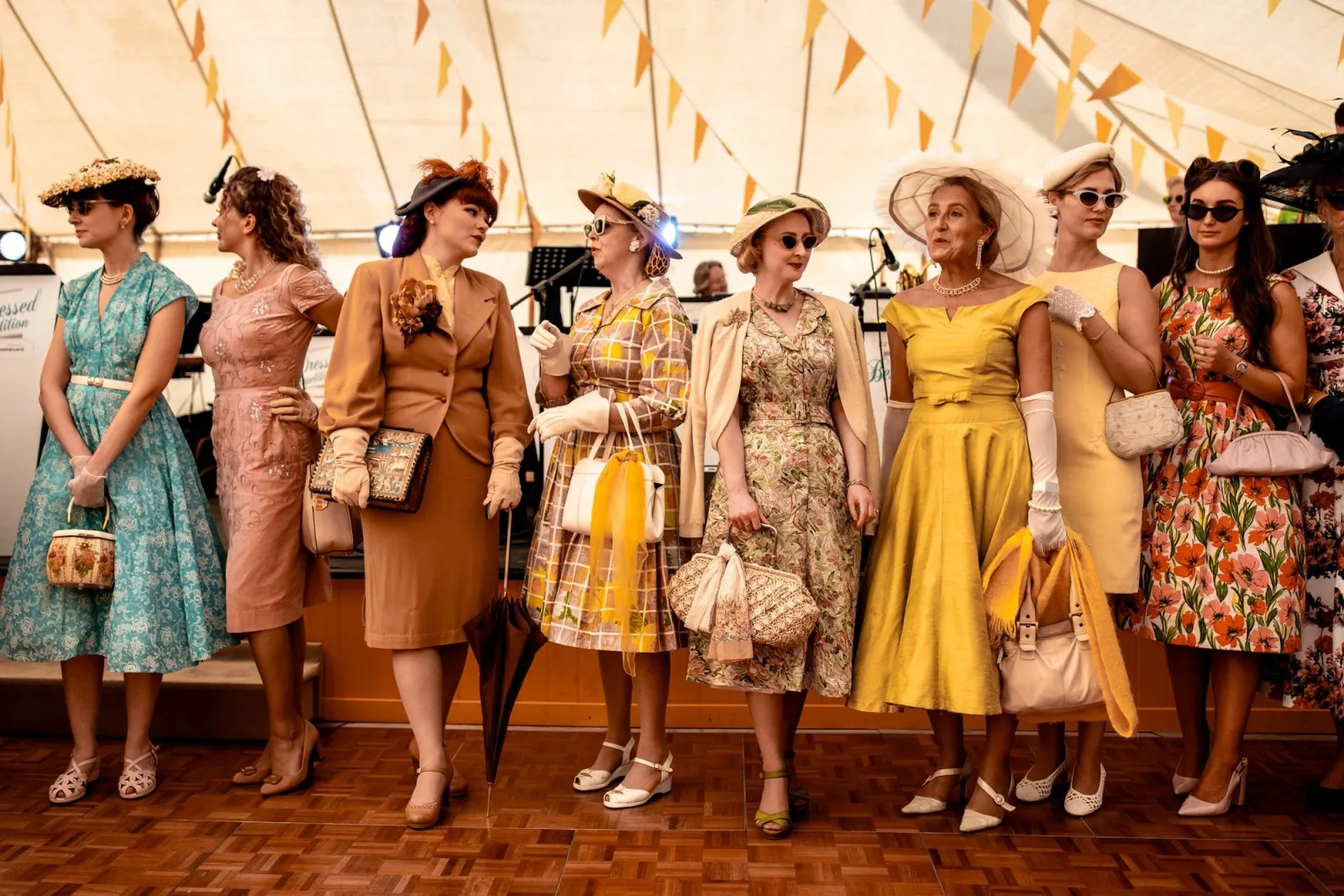 A row of women in 1950s dresses, hats and gloves at the Goodwood Revival.