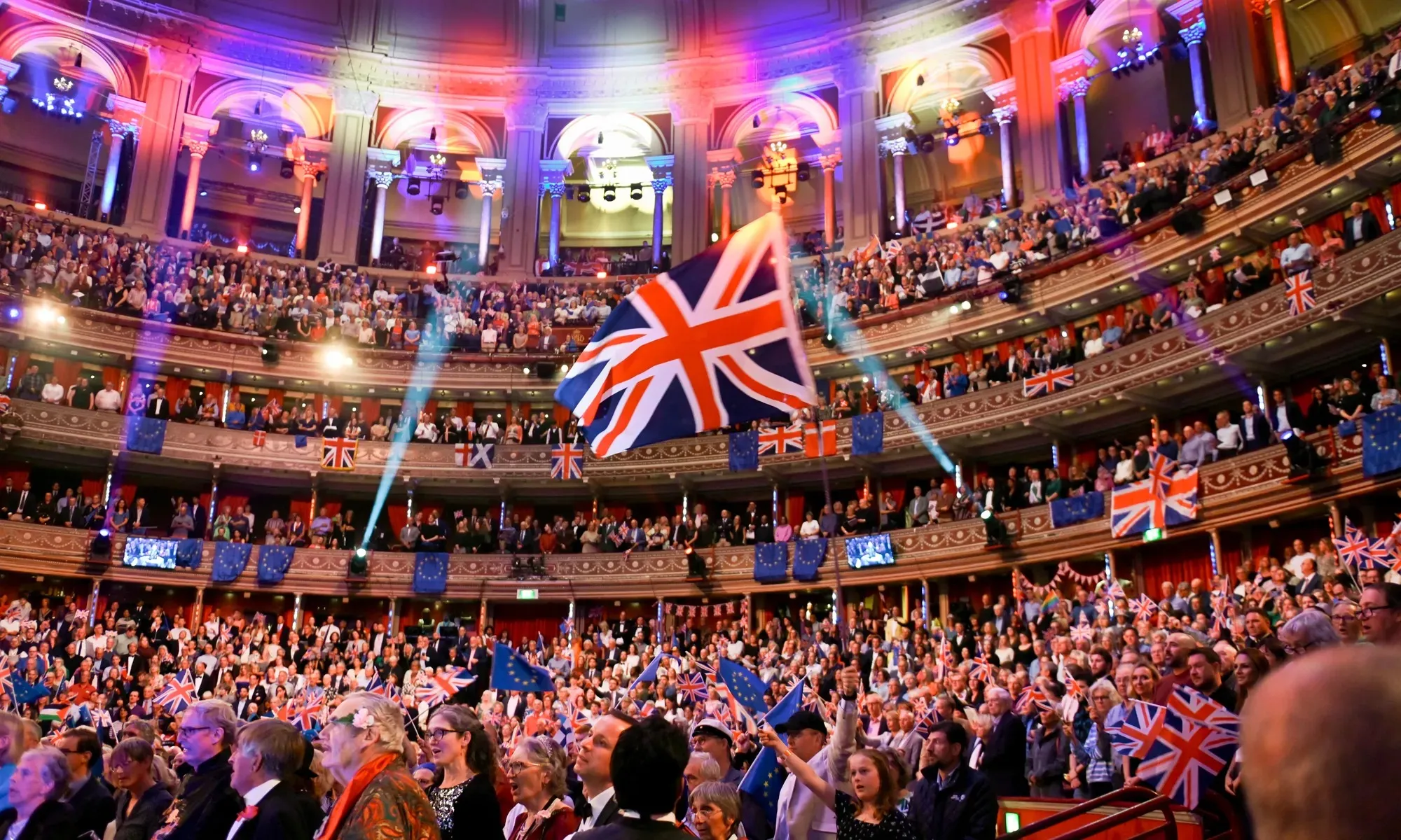 A Union Flag held up in the stalls at the Last Night of the Proms, with flags waving across the tiers of the Royal Albert Hall.