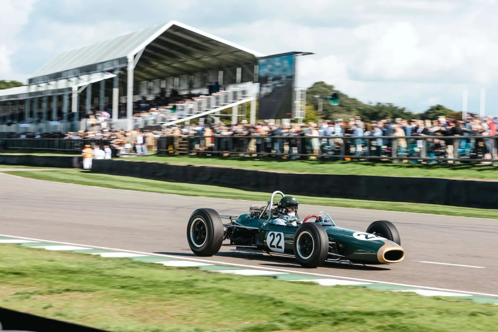 A green single-seater racing past the grandstand at the Goodwood Revival.