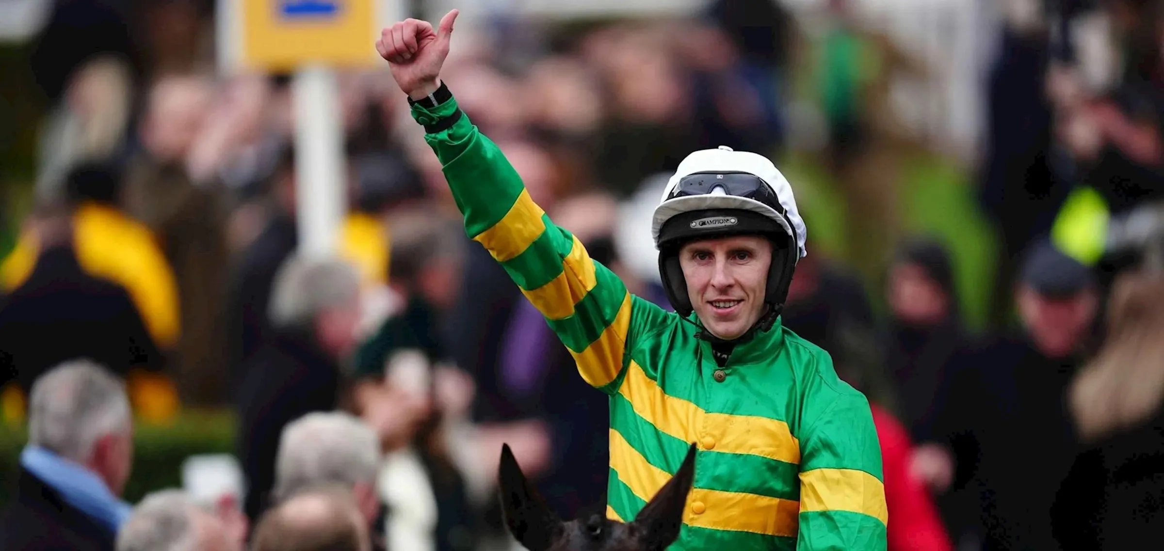 A jockey in green and gold hooped silks raising a fist in celebration at Cheltenham.