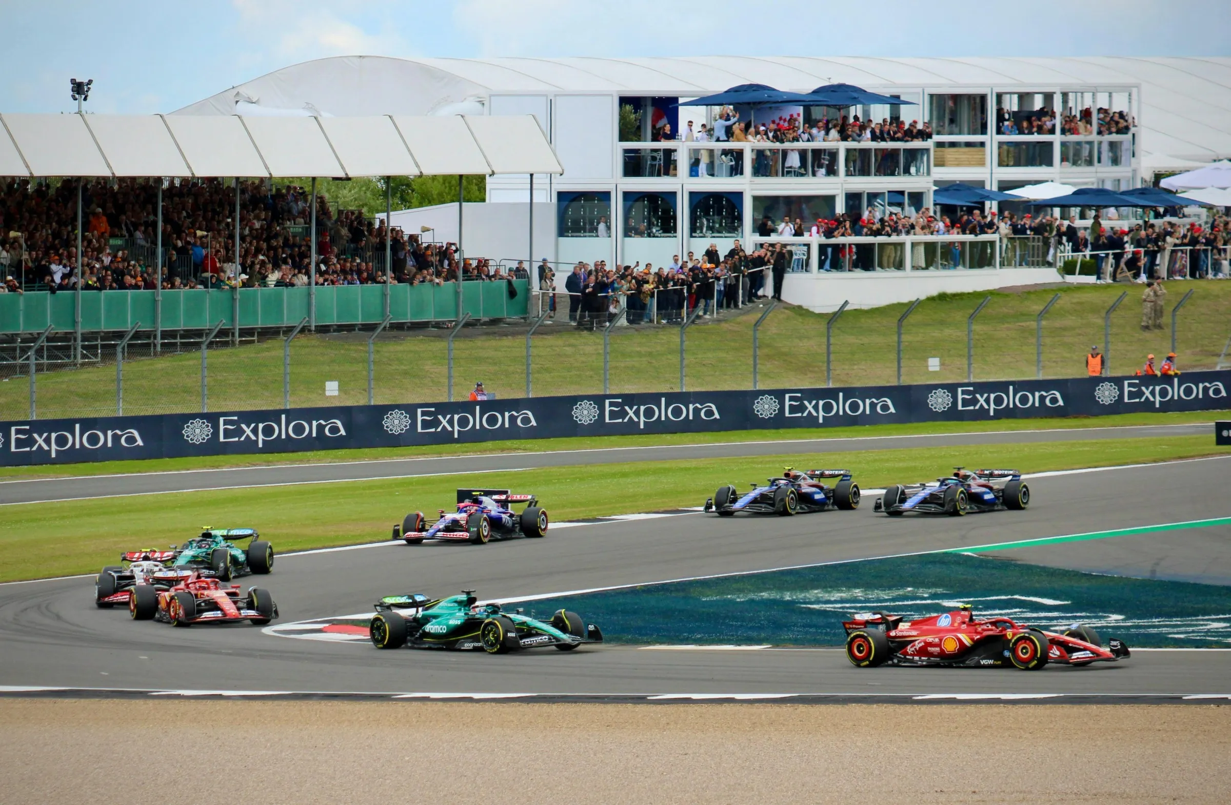 Formula One cars racing at Silverstone, one of them in green.