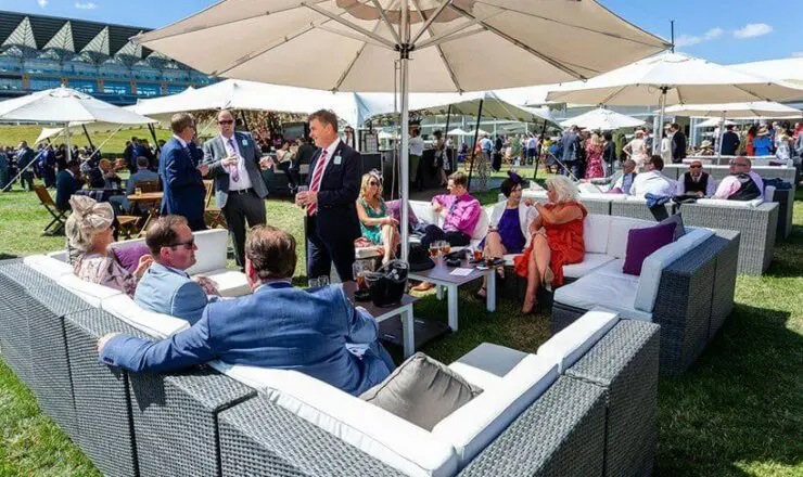 Image of a guests seated in their private seating area, with an umbrella shading guests from the sun