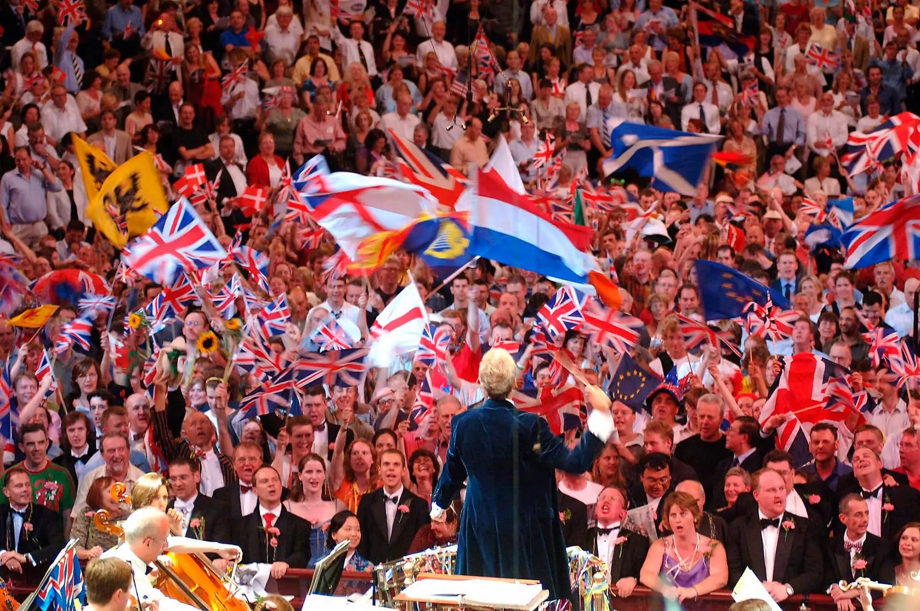 Image of conductor facing audience who are singing along to the orchestra at the proms
