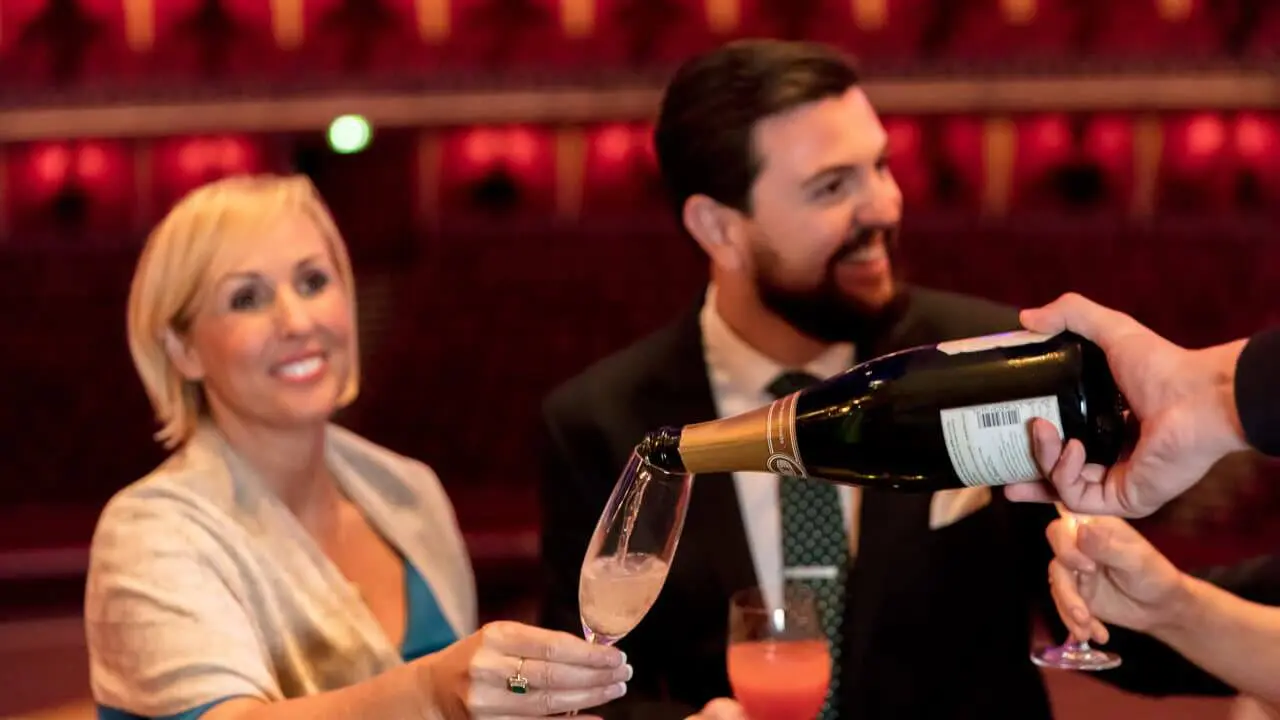 Waiter serving two guests their Champagne before the show starts