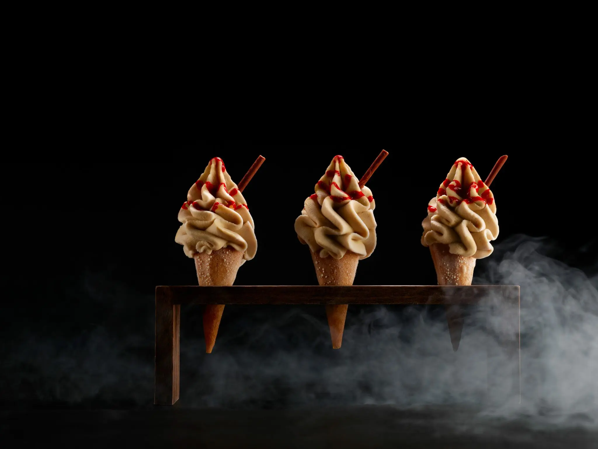Image of 3 dessert ice creams with strawberry sauce and a flake