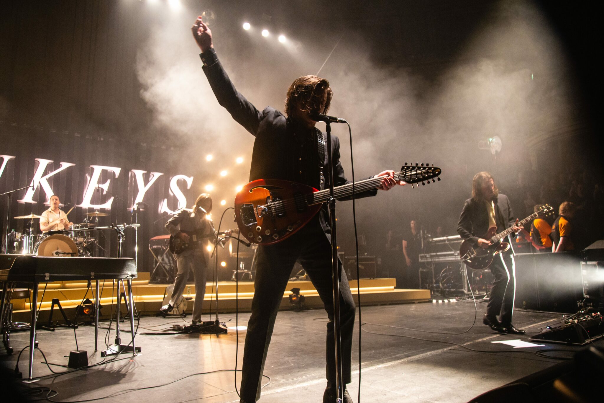 The Arctic monkeys performing on stage with Alex Turner in the centre of a smokey stage