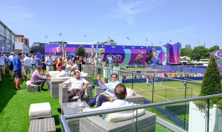Image of the rooftop garden at The Queens Club with guests sat on outdoor chairs overlooking the game