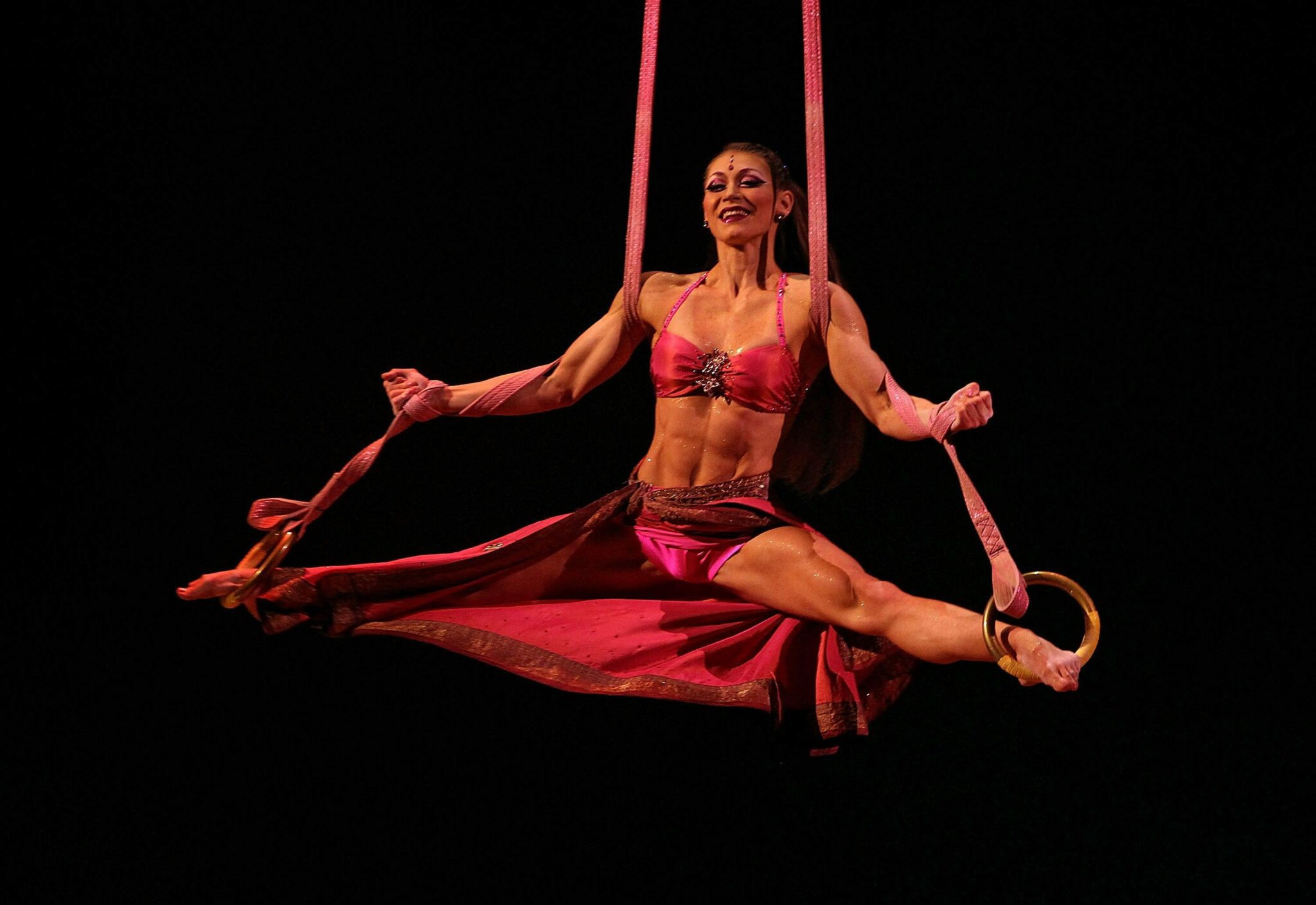 Female acrobat performing at Cirque, hanging off ribbons
