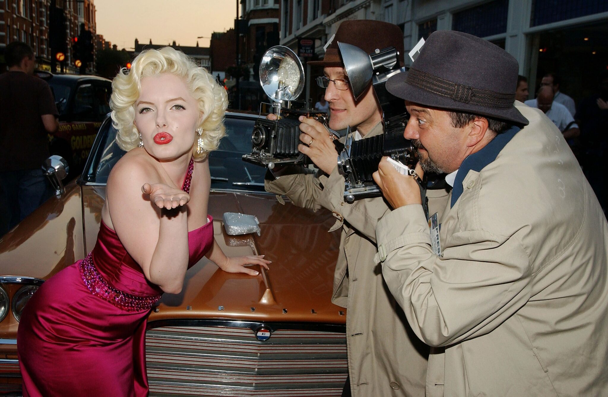 Image of a lady dressed up as Marylin Monroe and two men dressed up as photographers taking pictures of her