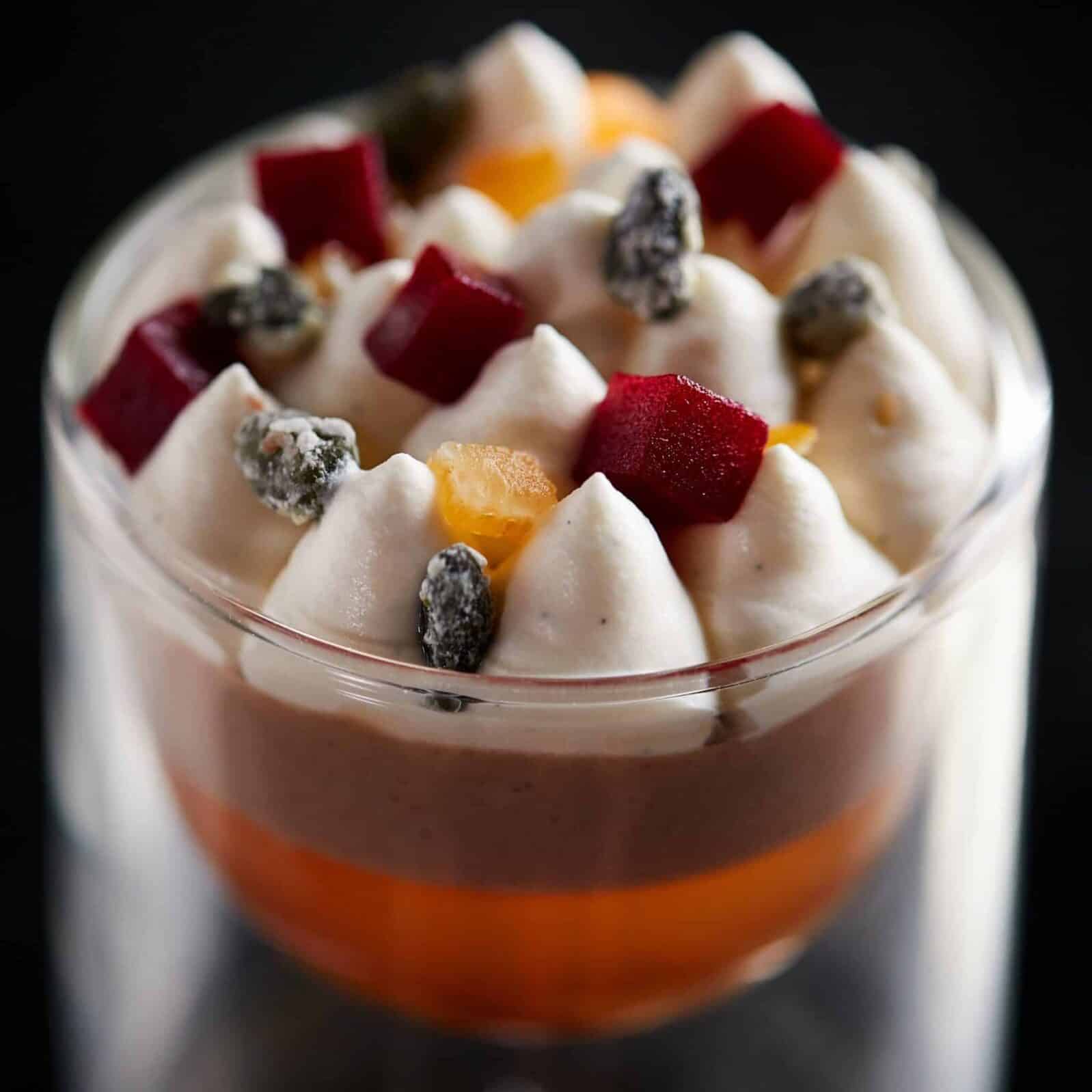 Image of a fruit compot dessert with whipped cream and dried fruit on top
