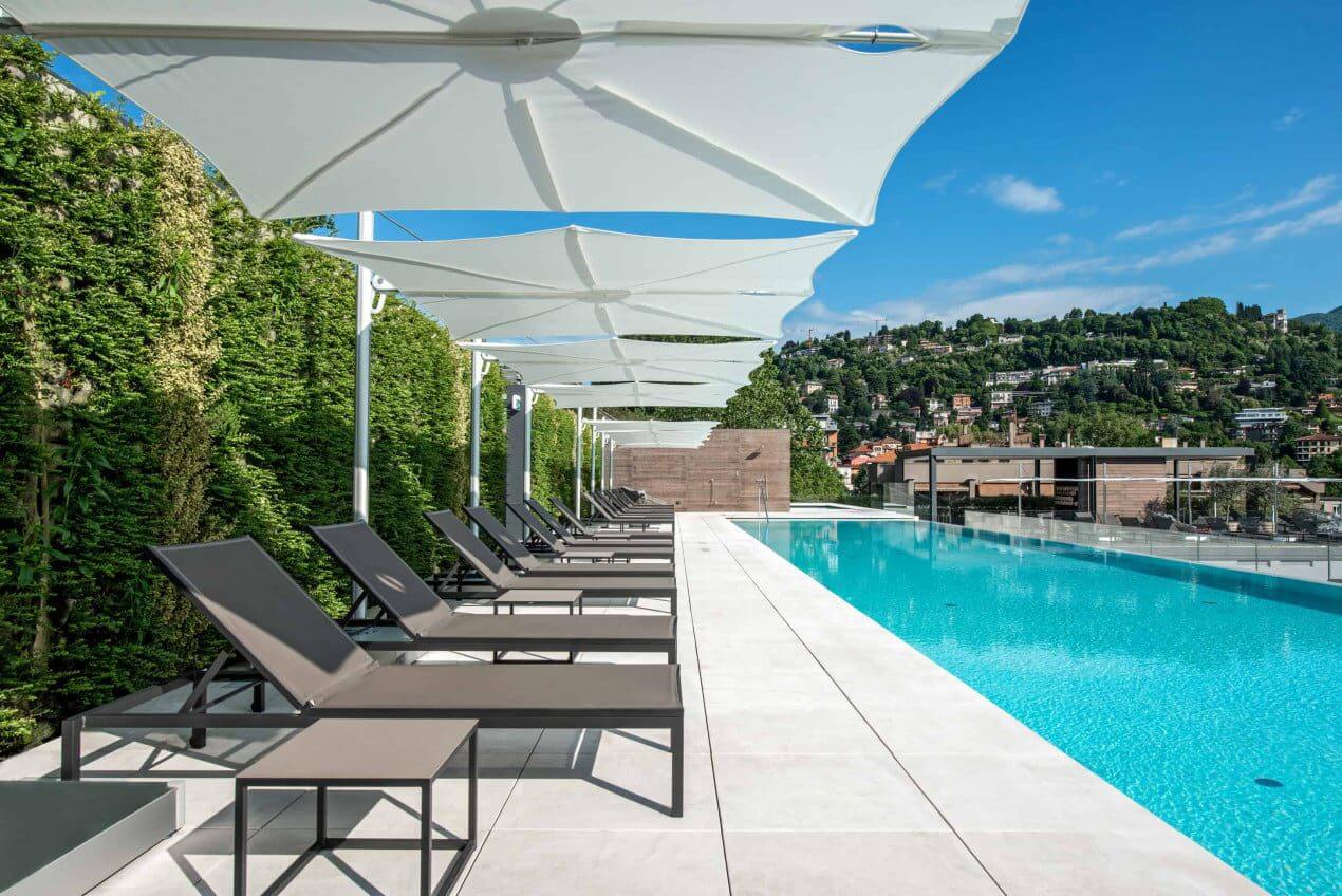 Image of the swimming pool and sunloungers and umbrellas outside the hotel