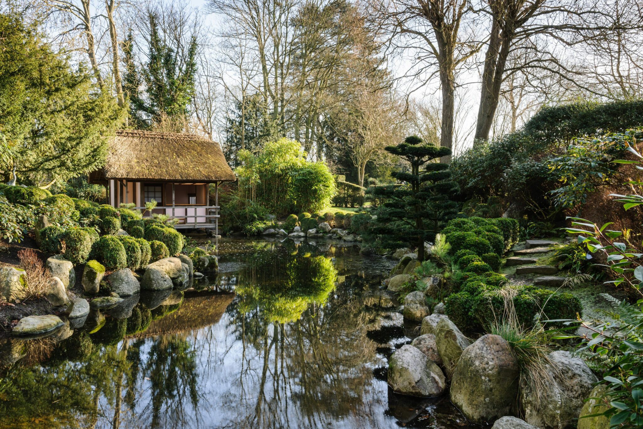 Image of an outdoor lake and water area in the gardens of Le Manoir aus Quat'Saisons with a boat house
