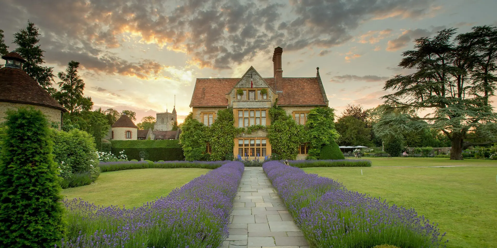 Le Manoir restaurant during the day time, a pathway leading up to the building with lavendar surrounding the path