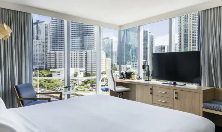 Image of hotel room with large glass windows overlooking the surrounding skyscrapers