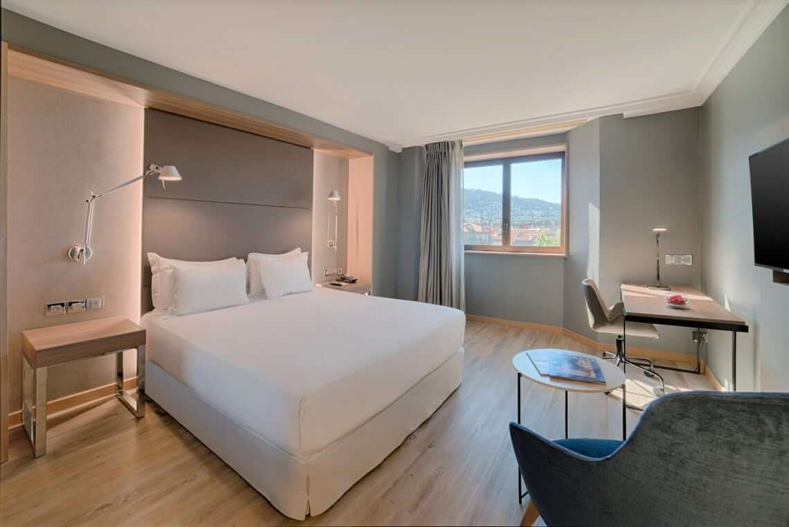 Image of the hotel room with a large double bed a small seating area with desk