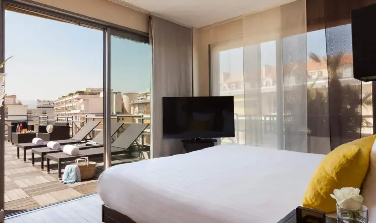 Image of hotel room with large double bed and tv, with doors onto a patio terrace