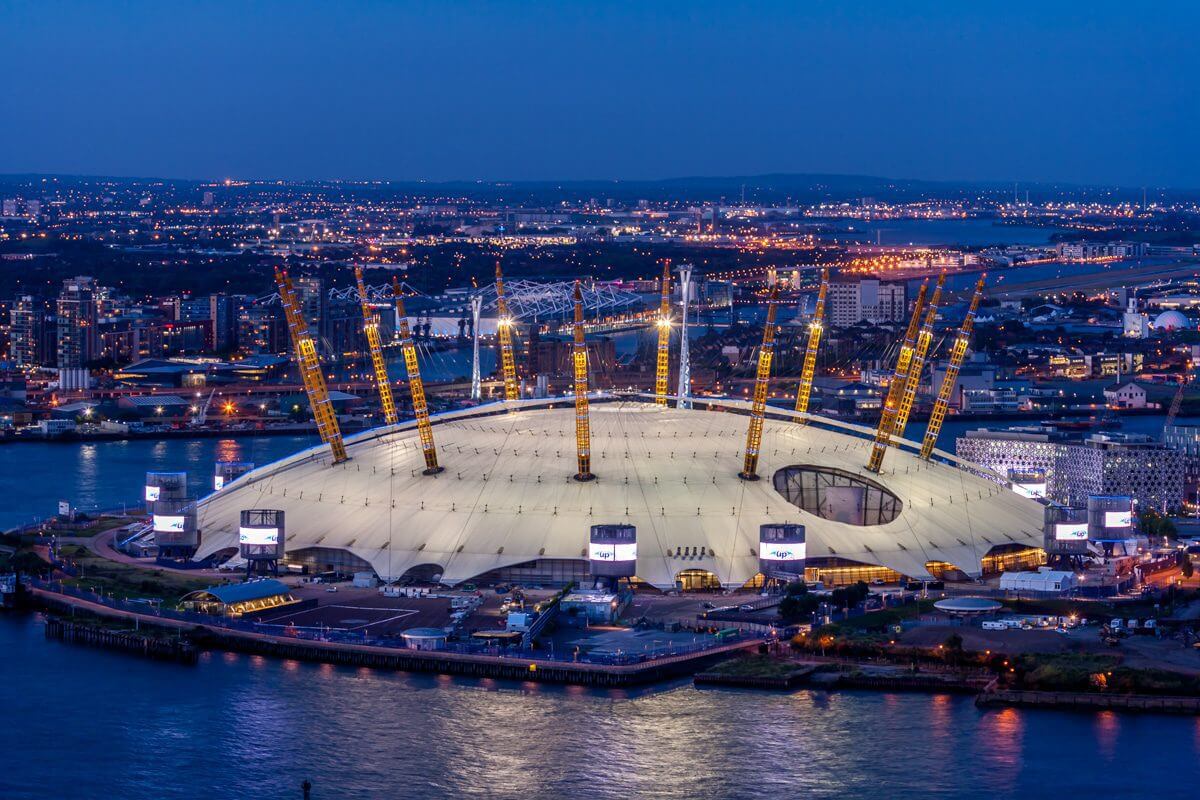 Image of the 02 Arena lit up at night with london skyscrapers in the background