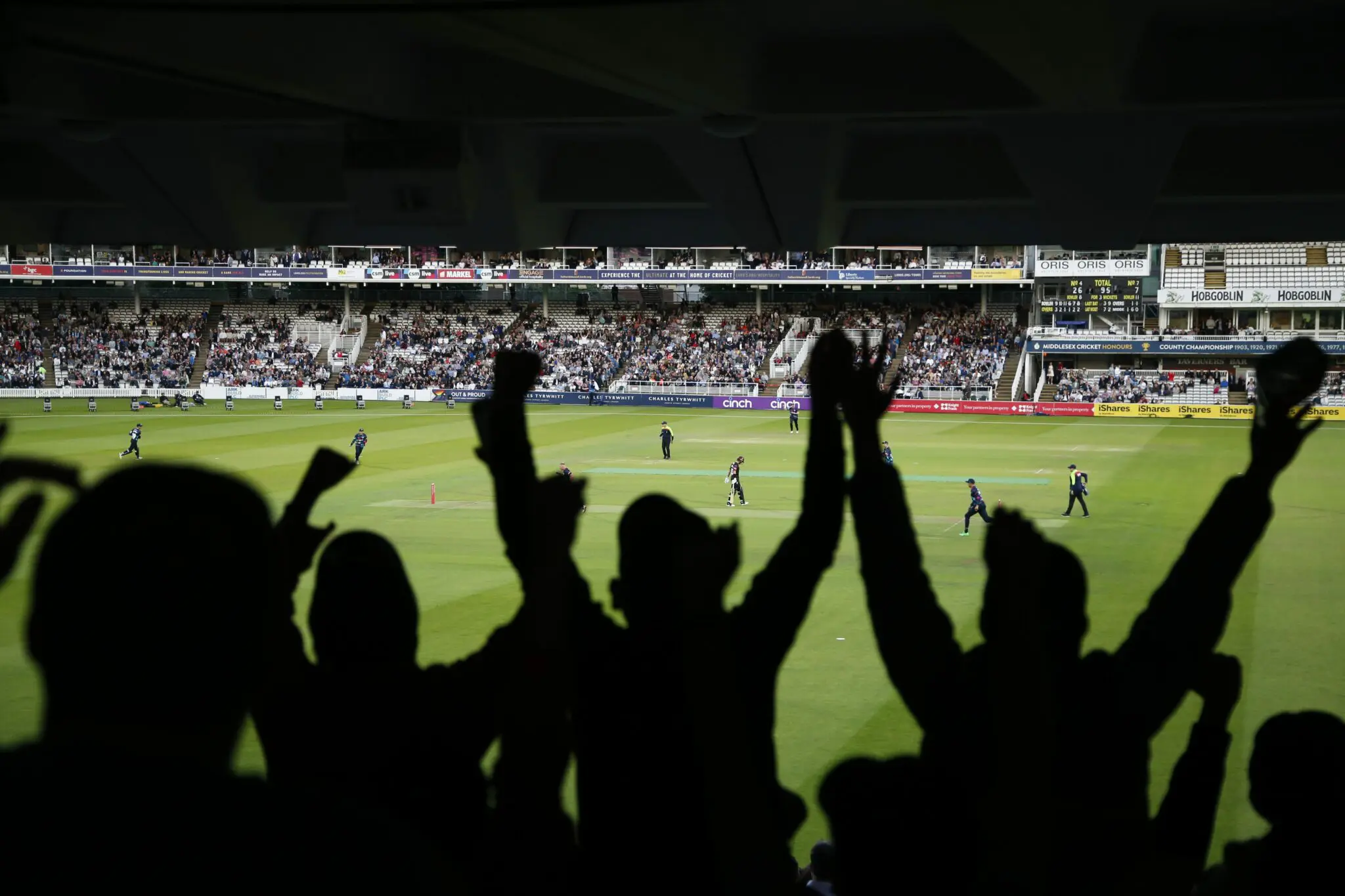 Crowd cheerying in the stands during a cricket match