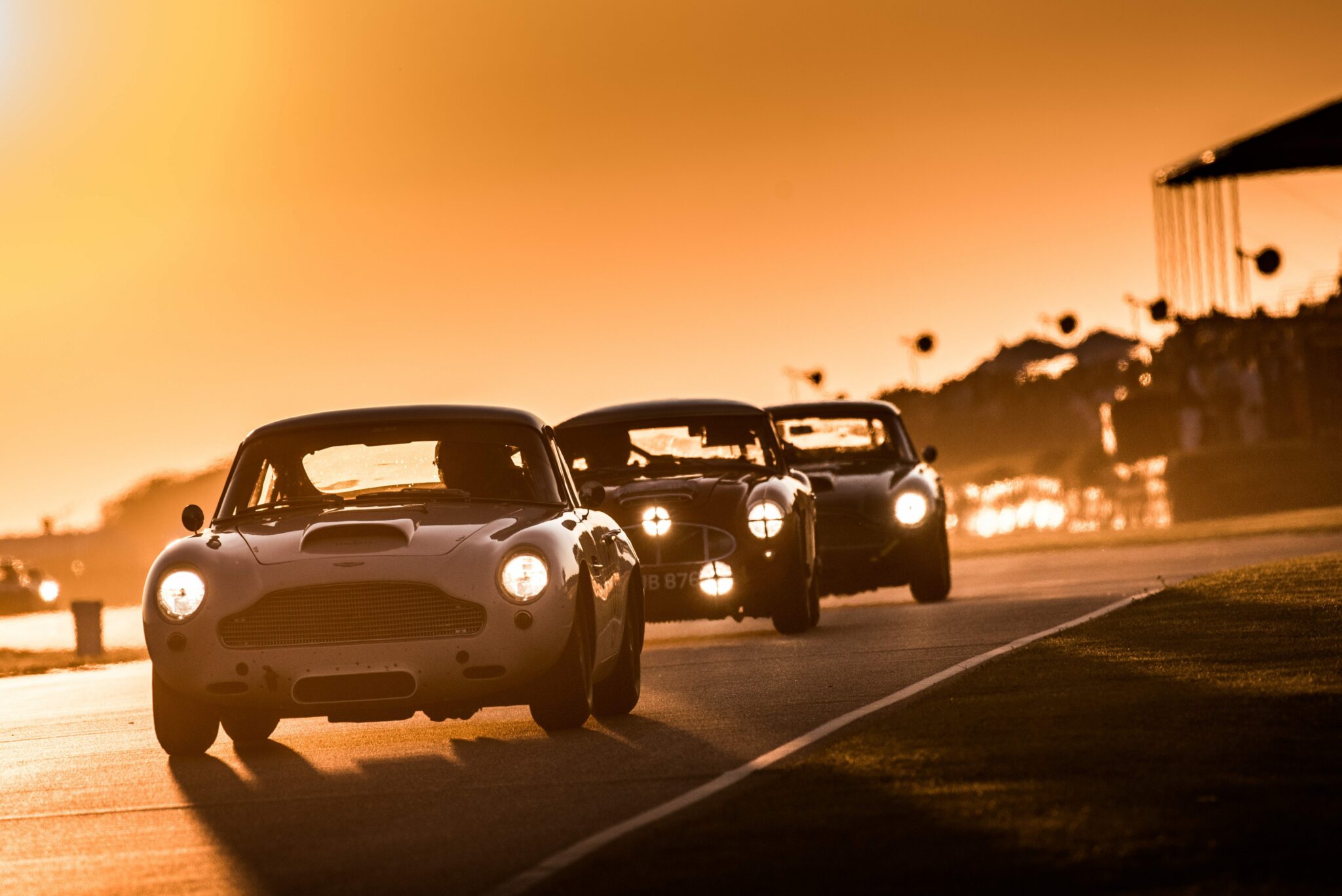 Vintage Goodwood race cars racing at sunset