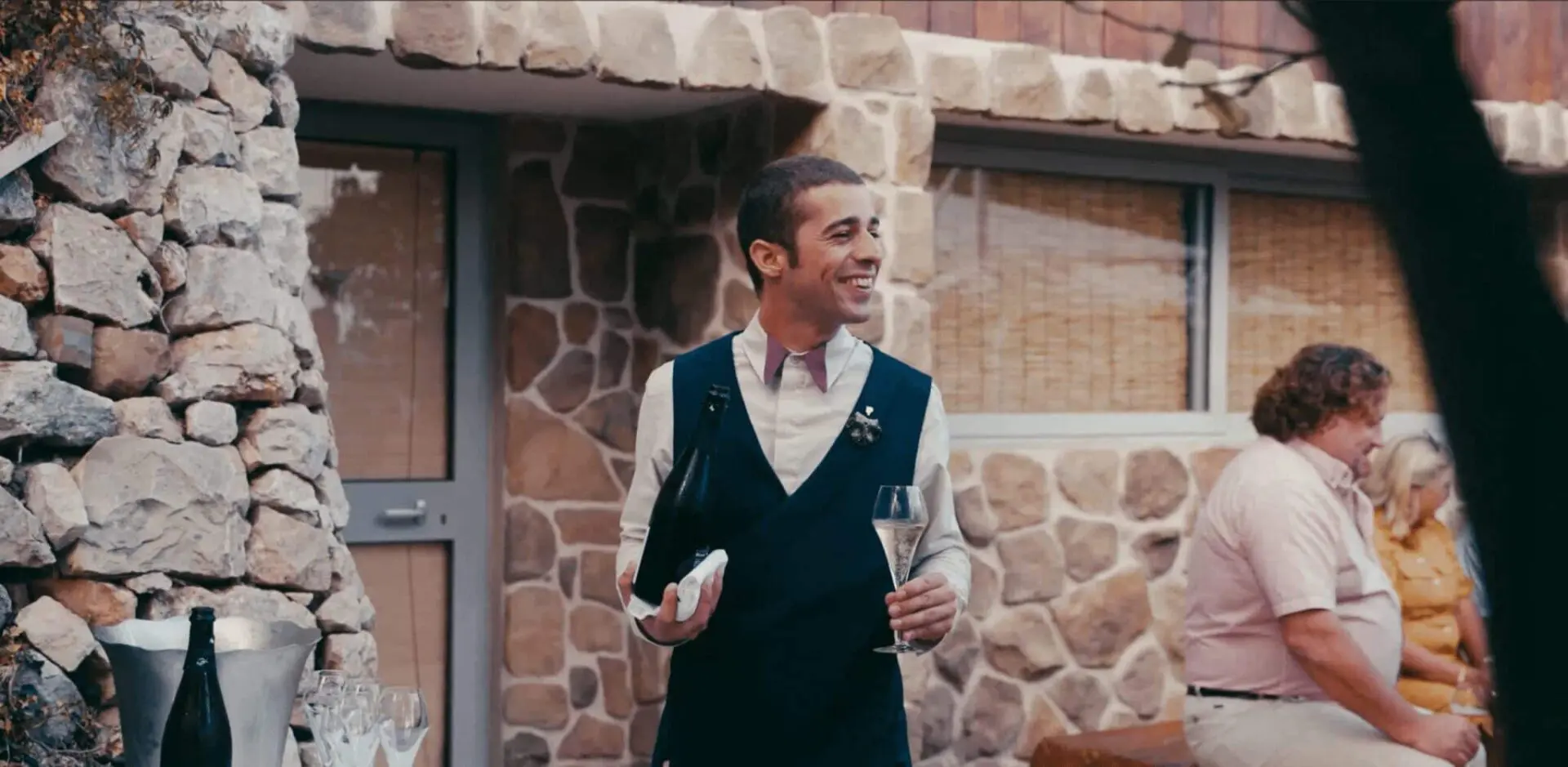 A waiter smiling pouring out a glass of wine