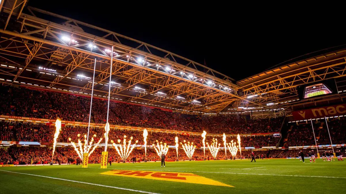 Image of the Principality Stadium lit up with fire displays and a busy crowd