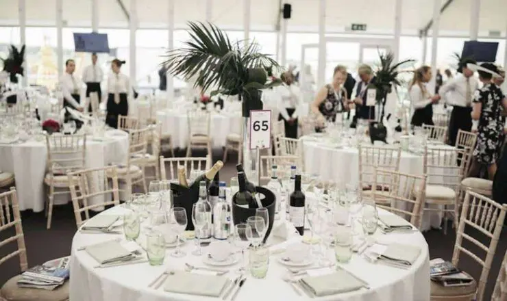 Image of a white decorative table within the marque with glasses and Champagne bottles