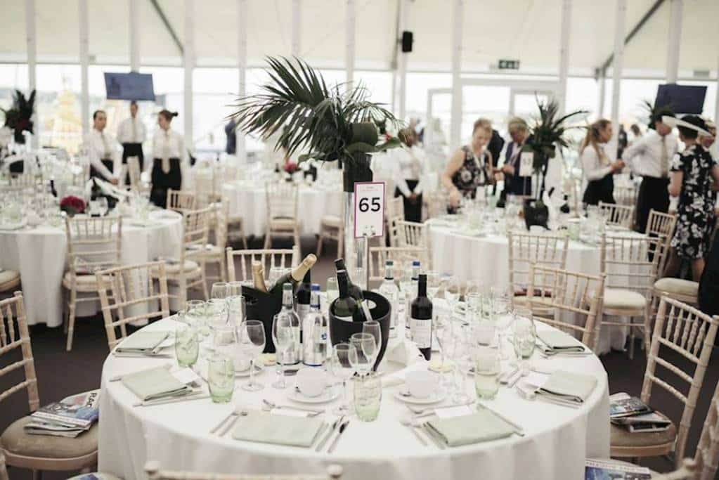 Image of a white decorative table within the marque with glasses and Champagne bottles