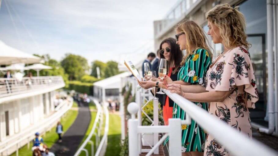 Image of ladies holding Champagne from their private box watching the race