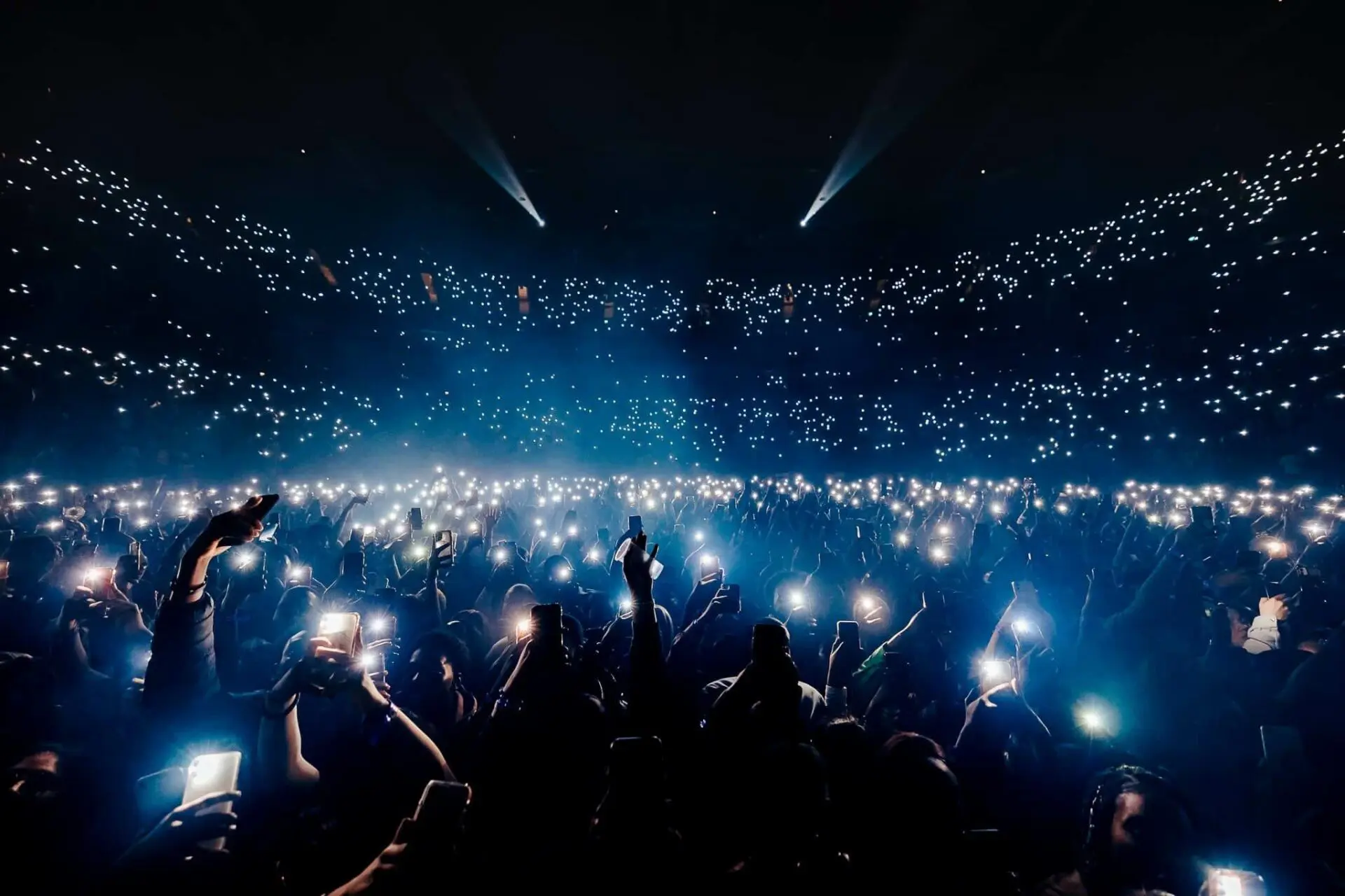 Image of people lighting up their phones to a band at the O2 Arena in London