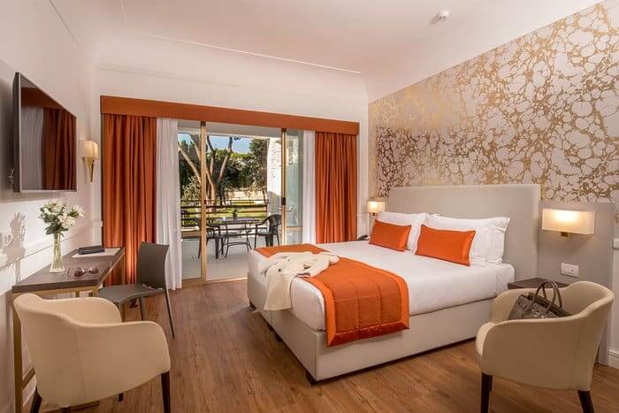 Image of hotel room with large, beautiful double bed, seats arranged around the room and large balcony doors