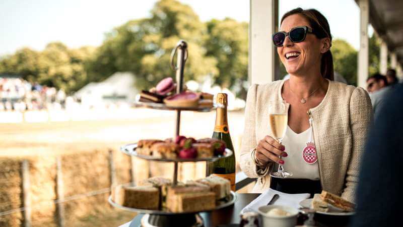 Image of a happy lady eating an afternoon tea by the trackside pavilion